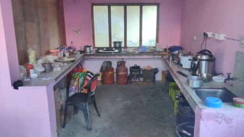 a cluttered kitchen with a sink and a counter top at Kedar Kunj in Phata