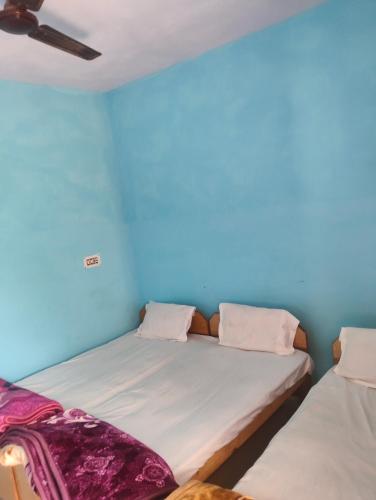 two beds in a room with a blue wall at Kedar Kunj in Phata