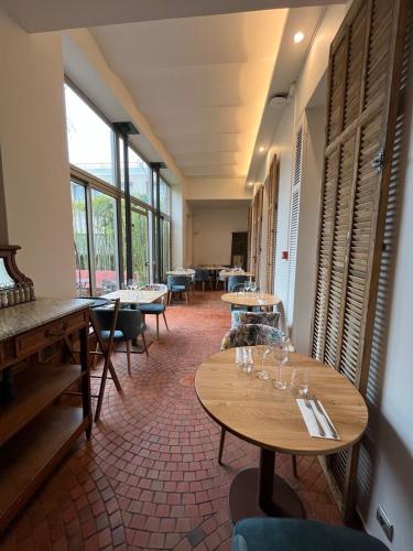 a dining room with tables and chairs and windows at Le Domino Chambres d'Hôtes et Restaurant in Draguignan