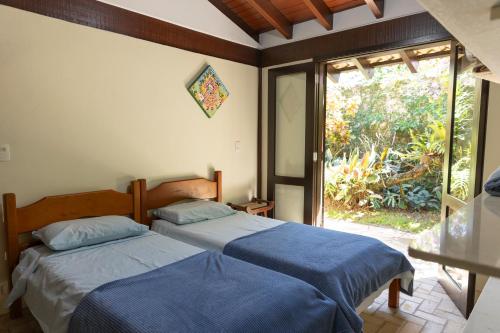 two beds in a room with a window at Casa Jataí Guest House in Barra do Sahy