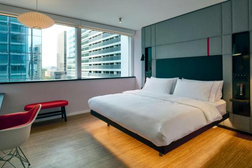 a bedroom with a bed and a chair and a window at citizenM Austin Downtown in Austin