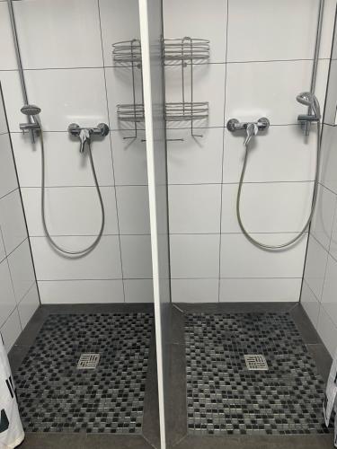 a bathroom with two showers and a tiled floor at GARLAND Rooms in Bremen