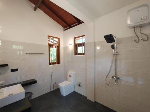 a bathroom with a shower and a toilet and a sink at Nature Velora Villa in Tangalle