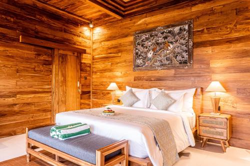 a bedroom with a bed in a room with wooden walls at Kubu Tama Villa in Tegalalang
