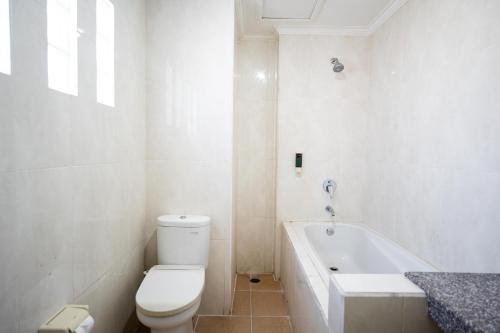 a white bathroom with a toilet and a bath tub at Nusa Dua Moon Hotel in Nusa Dua