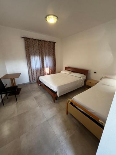 a bedroom with two beds and a desk in it at L'imbarco ROOMS in Badolato Stazione