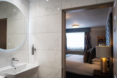 a bathroom with a sink and a mirror and a bed at Beaufort Hotel in Inverness