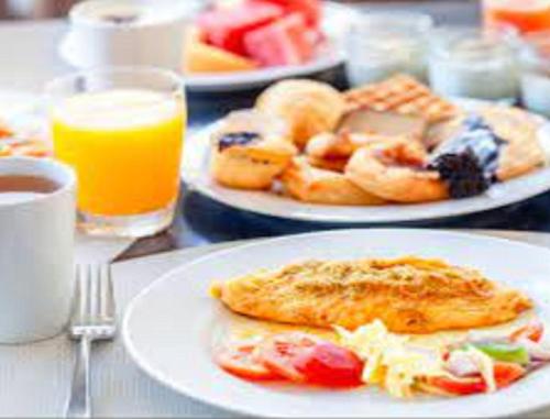 a table with plates of breakfast foods and orange juice at Karma Cairo Hotel in Cairo