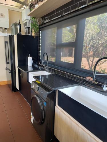 a kitchen with a sink and a washing machine at Hartbeespoort Escape Hot Tub and Mountain Views in Skeerpoort
