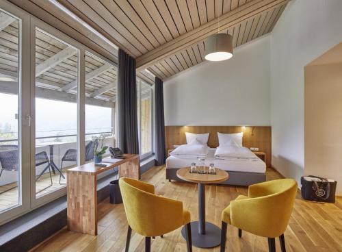 a bedroom with a bed and a table and chairs at ElzLand Hotel Pfauen WELLNESS & SPA in Elzach