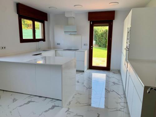 a kitchen with white counters and a marble floor at Ecopausa Somió - Gijón in Gijón