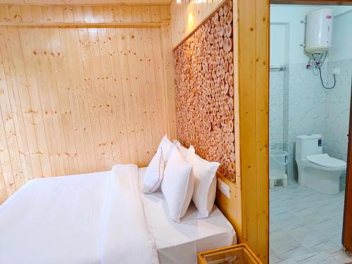 a bedroom with a white bed and a toilet at Riverside Bliss Cottages in Gushaini