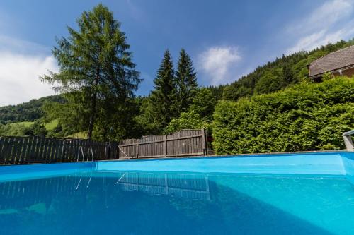 a blue swimming pool with a fence and trees at Gasthof zum Hammer in Göstling an der Ybbs