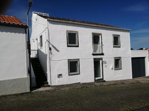 a white building with a staircase in front of it at Casa do Roberto in Lajes das Flores