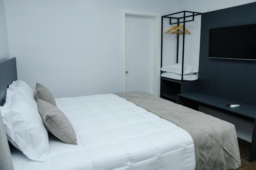 ein Schlafzimmer mit einem weißen Bett und einem Fernseher in der Unterkunft Caza Flat Hotel in Constantina