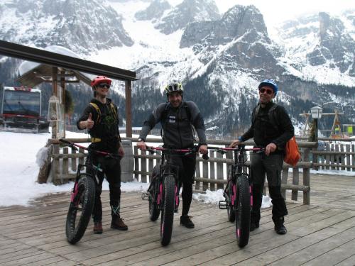 three men are standing with their bikes on a boardwalk at Rifugio La Montanara in Molveno