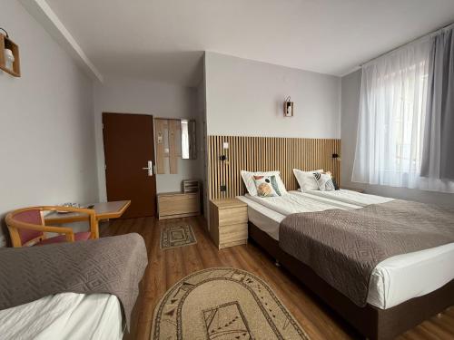 a hotel room with two beds and a window at Lázár Pension & Restaurant in Gheorgheni