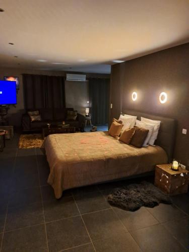 a bedroom with a large bed and a flat screen tv at Suites et Wellness des Champs-Elysées in Ciney