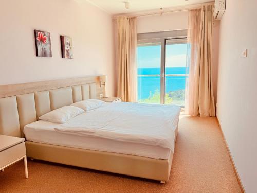 a bedroom with a bed and a large window at Hillside Apartment with Sea View in Budva