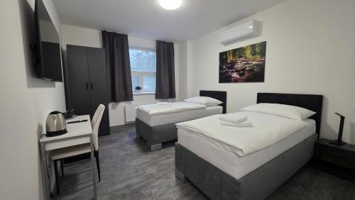 a hotel room with two beds and a desk and a desk at Apartmány Koruna in Ostrava