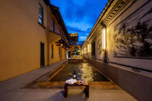 a canal with a table and bottles of wine at Aofeng Tangquan Secluded Villa in Jianchuan
