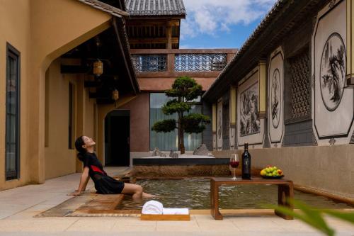 a woman sitting in a pool of water in a building at Aofeng Tangquan Secluded Villa in Jianchuan