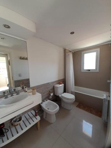 a bathroom with a tub and a toilet and a sink at Departamento Miranda in Villa Gesell
