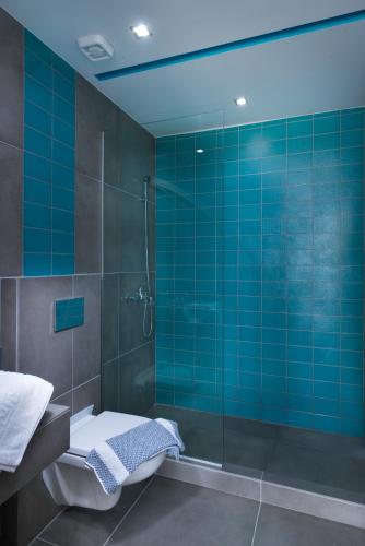 a blue tiled bathroom with a shower and a toilet at Fresh Mare Apartments in Limenaria