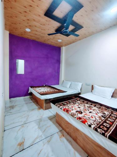 a bedroom with two beds and a purple wall at Jay shree Kedar room in Ujjain