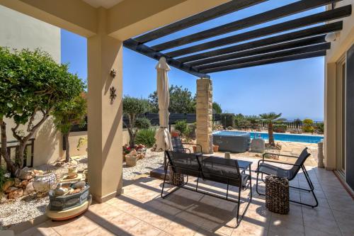 a patio with a table and chairs and a pool at Seaview Villa in Peyia | Private pool & jacuzzi by VICHY Holidays in Paphos