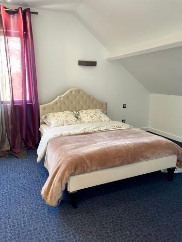 a bedroom with a large bed with red curtains at Maison de vacances campagnes in La Celle-Guénand