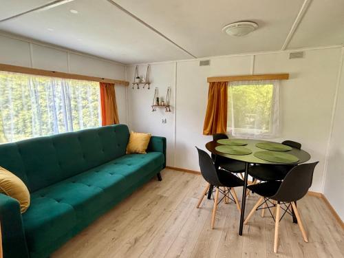 a living room with a green couch and a table at Domek z widokiem na las in Nielisz