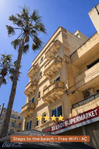 a building with a palm tree in front of it at Arzella Apartments Xlendi, Premium 2BR, Bus Stop & Market Opposite in Xlendi