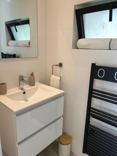 a white bathroom with a sink and a mirror at Cocon proche de Lyon in Neyron