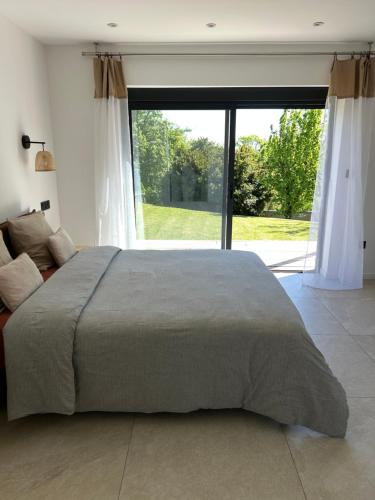 a bedroom with a large bed and a large window at Cocon proche de Lyon in Neyron