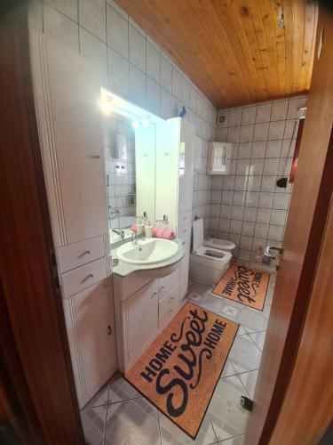 a bathroom with a sink and a toilet and a welcome mat at Apartmani Bistrivoda in Vogošća