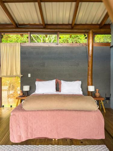 a bedroom with a large bed with a pink blanket at Loft Pitangueira in Petrópolis