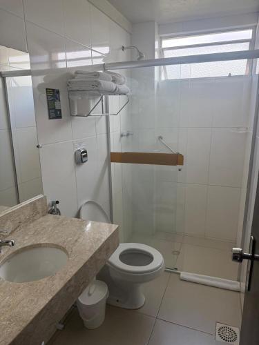 a bathroom with a toilet and a sink and a shower at Hotel São Luiz in São Gabriel