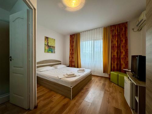a small bedroom with a bed and a television at Mellys Haus in Mangalia