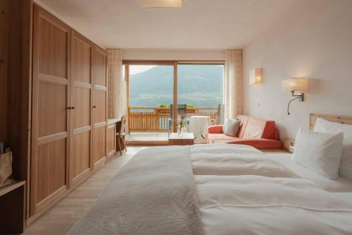 a bedroom with a large bed and a balcony at Niedermair Nature Retreat in Parcines