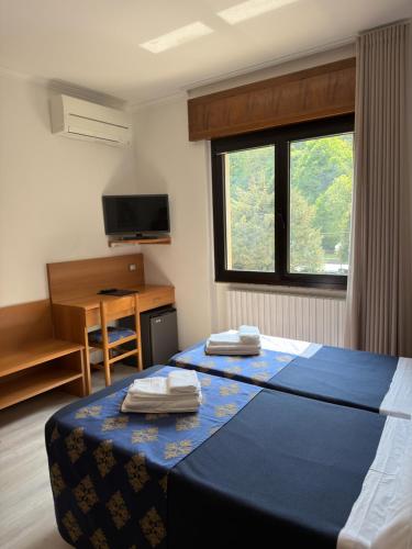 a room with a bed and a desk and a window at Hotel Merloni in Grandola ed Uniti