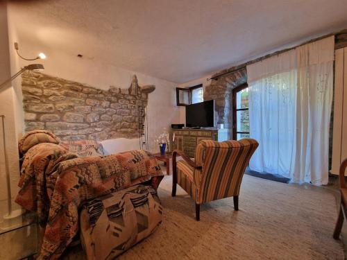 a bedroom with a bed and a stone wall at Le Coccinelle in Pallerone