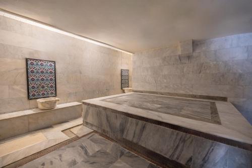 a bathroom with a large tub and a stone wall at Sentinus Beach Hotel in Kuşadası
