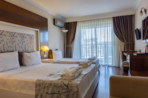 a hotel room with two beds and a desk at Sentinus Beach Hotel in Kuşadası