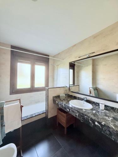a bathroom with a sink and a large mirror at CASA DE AREAS in Sanxenxo
