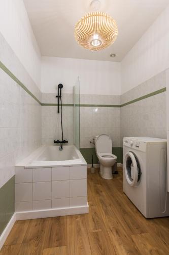 a bathroom with a tub and a washing machine at Maison avec parking la Flocellière in La Flocellière