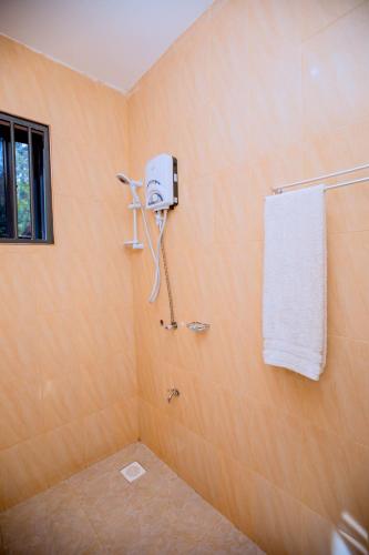 a bathroom with a shower with a towel on the wall at Clisa Rest House in Karatu