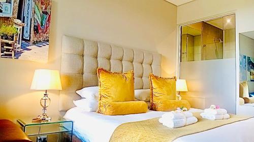 a bedroom with a large bed with yellow pillows at Menlyn Maine Residences - Napoli with king sized bed in Pretoria