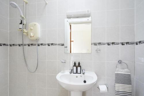 a white bathroom with a sink and a mirror at Willows in Calbourne