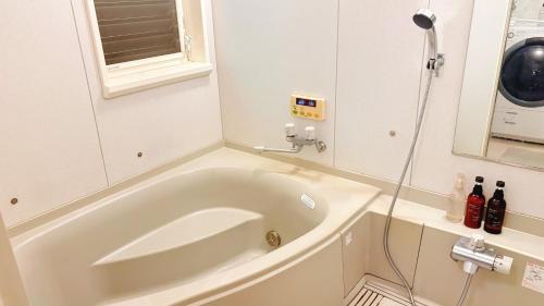 a white bath tub in a bathroom with a shower at 民泊やまねこ in Yachi